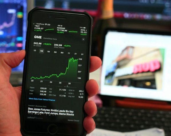 Acima, imagem retirada de um banco gratuito de fotos mostra um celular e, na tela, ações de mercado