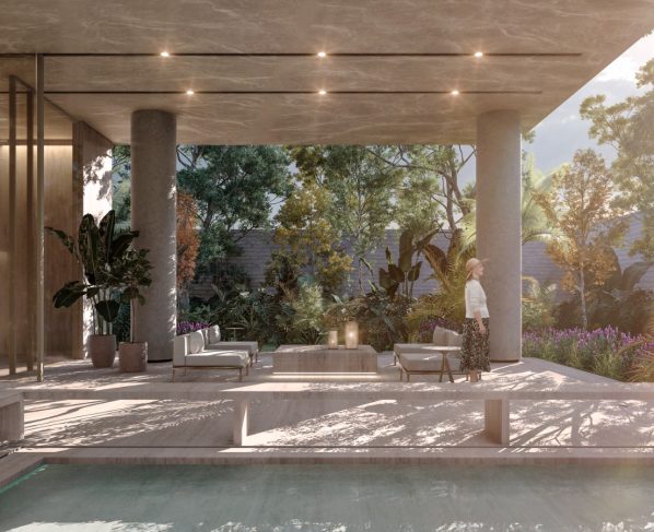 Área comum de edifício residencial com pé-direito alto, pilares de concreto e mobiliário contemporâneo. Uma mulher caminha pelo ambiente iluminado por luz natural.